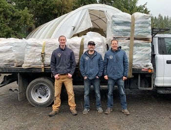 Three men standing in front of a truck bed full of pet food