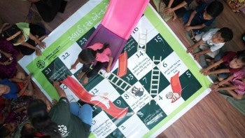 Children play life-sized game of slides and ladders