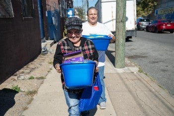 Two people carrying donated pet food and supplies