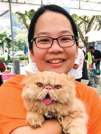 Woman smiling, holding a tan cat.