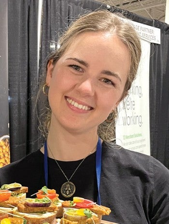 Woman smiling, holding a plate of food. 