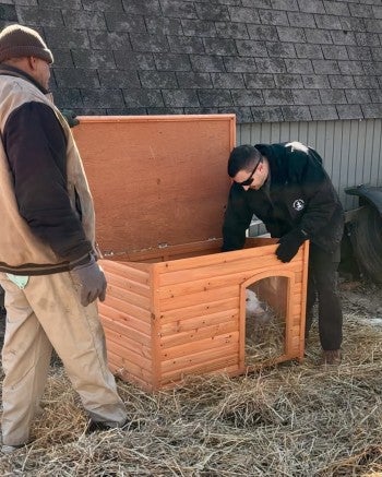 Two people installing a doghouse