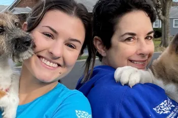 Two women are holding puppies and smiling at the camera