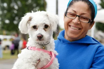 Smiling woman holding her white dog