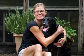 Woman and her black dog on back porch of their home