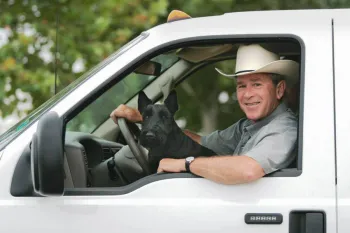 George W Bush drives a truck while Barney sits on his lap