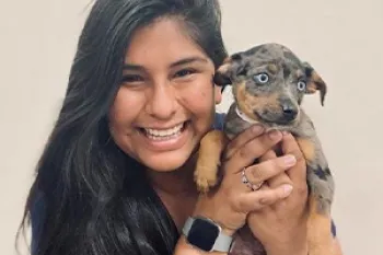 Smiling woman with dark hair holding a puppy