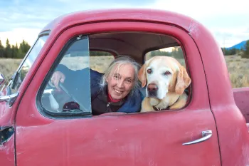 Jane Goodall in a red truck with a dog.