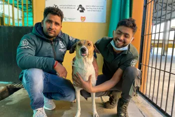 Two people pose with a dog