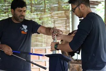 Two men carefully handle a snake contained safely within a bag