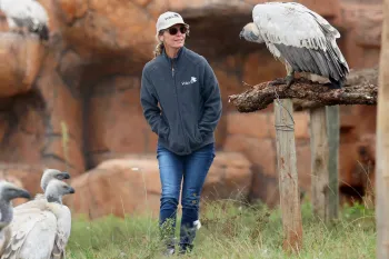 A woman, walking outside at a vulture conservation center.