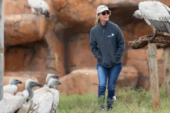 A woman, walking outside at a vulture conservation center.