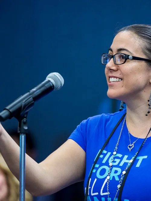 A smiling woman speaks into a microphone