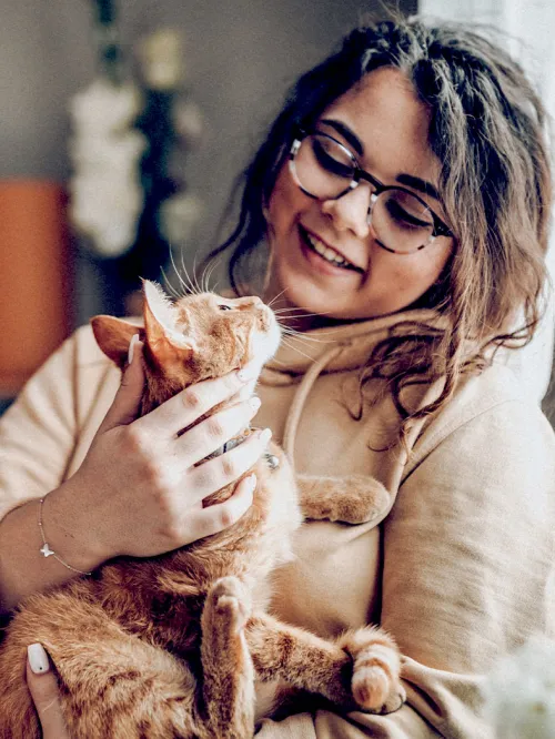 A woman holds a cat in her arms as they look lovingly at each other