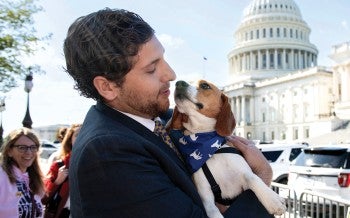 Man holding a beagle in front of the Capitol building in Washington, D.C.