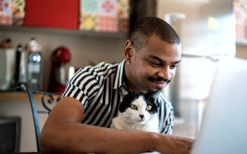 A man and his cat look at his laptop